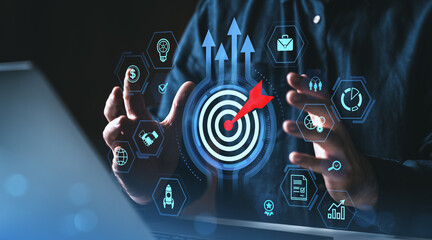 Poster - Business target and growth strategy concept with digital icons and red dart hitting bullseye surrounded by hands on dark background.