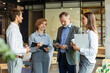 © ty - Group of business people standing together and discussing their work and projects, having a team meeting in an office.