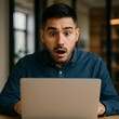 © SONG IL GEUN - Hombre hispano sorprendido mirando una computadora portátil en la oficina