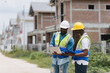 © nikomsolftwaer - Two engineers in safety gear inspecting a building under construction. black engineers inspect ceiling infrastructure at a construction site