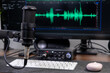 © Alina - Professional black condenser microphone setup in a home audio studio, with digital sound waveforms displayed on a computer screen for podcast and music production