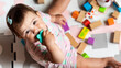 © Pixel_Studio_8 - Cute baby girl playing, learning and developing with colorful educational toys. Adorable toddler chewing a sensory toy surrounded by blocks. Fun, health, childhood, creativity and play