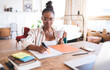 © BullRun - Young black woman in striped shirt sipping coffee while working from cozy bedroom, enjoying calm freelance lifestyle with planner and laptop on rustic wood table
