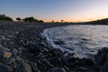 Wall Mural - pebbly coastline with clear sky at dawn.