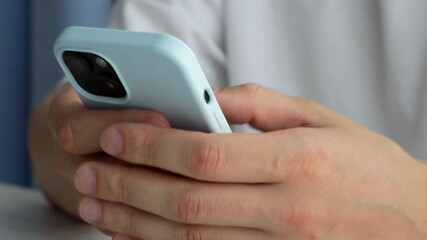a man in a white t-shirt with a mobile phone in his hands in a bright office during the day. modern 