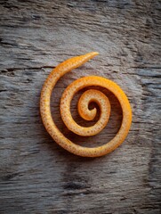 Poster - Decorative Orange Peel Spiral Elegantly Displayed on Rustic Wood Background in a Clean Layout