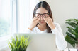 © KMPZZZ - Eye problem concept, fatigue asian young woman tired eyes, irritated rubbing eye dry relief vision pain after work on laptop computer, eye strain, hand holding glasses, suffer migraine, bad blurry.