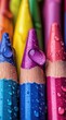© Xin Yan - A close up view of vibrant rainbow crayons with water droplets highlighting their colorful surfaces and creating a mesmerizing artistic effect