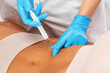 © Dimid - Aesthetic cosmetologist makes lipolytic injections to burn fat on the body of a woman. Female aesthetic cosmetology in a beauty salon.Cosmetology concept.