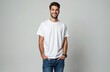 © Vadym - Handsome young man smiling confidently wearing white t-shirt, blue jeans against plain grey background. Dark hair, beard, looks directly at camera with cheerful, positive expression, hands in pockets.