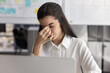 © fizkes - Tired woman sits at desk with laptop, closing dry or irritated eyes, rub nose bridge to reduce pain, exhausted from prolonged screen time, feeling overwhelmed or stressed due to information overload
