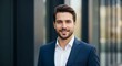 © adstockvision - Portrait of a smiling man in a suit with a blurred building background