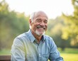 © Vadym - Happy senior man with grey beard smiles broadly, sitting outdoors in park on sunny day. Mature, active, retired male exudes vitality, enjoyment of life. Casual blue shirt worn in warm weather