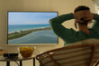 © New Africa - Young man watching travel show using video projector at home