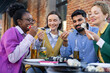 © sofiko14 - Diverse group of friends enjoying sushi and drinks outdoors, creating a relaxed and joyful dining experience.