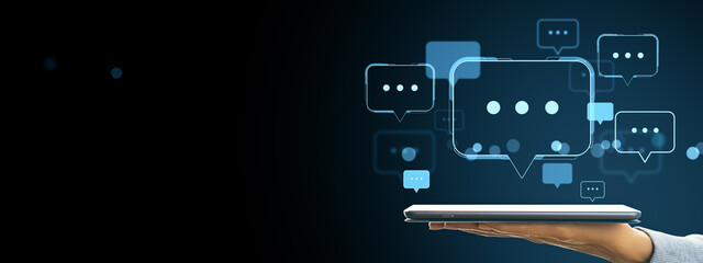 Poster - Digital chat communication concept with speech bubbles floating above a tablet device held by a hand on a dark background.