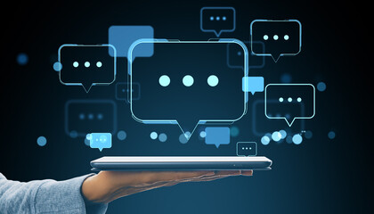 Poster - Digital communication interface with glowing speech bubbles emerging from a tablet held by a hand on dark background in modern tech concept.