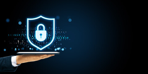 Fototapete - Digital shield with padlock icon floating over tablet in business hand on dark background symbolizing cybersecurity and data protection concept.