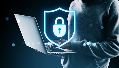 Fototapete - Cybersecurity concept showing person using laptop with glowing digital padlock shield icon symbolizing data protection and online privacy safety system.