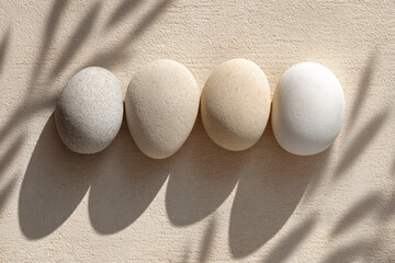 Aufkleber - Smooth stone ovals arranged in row on textured beige surface with soft natural shadows, creating calm and minimal abstract health focused layout