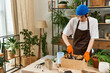 © Bliss - Handsome young man engages in plant transplanting amid studio greenery