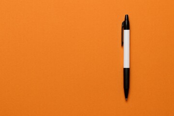 Poster - Elegant Office Desktop Background Featuring a Pen on a Vibrant Orange Surface