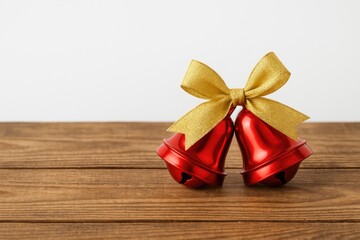 Poster - Red holiday bells adorned with a golden ribbon on rustic wooden planks