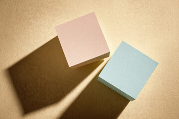 Aufkleber - Pink cube blue cube abstract background overlapping shadow beige surface minimal style geometric shape textured soft color modern art. Two pastel colored cubes casting long overlapping shadows