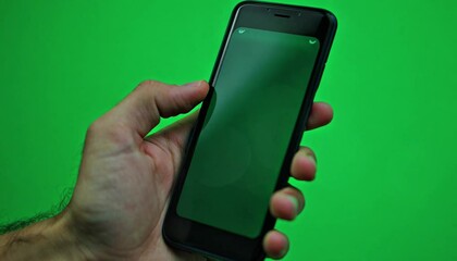 Poster - Hand Holding Smartphone with Green Screen and Bokeh Effect Against a Green Background