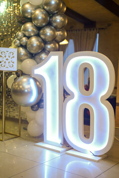 Decoration as a background for photography with white and gray balloons, glitter, neon sign Happy Birthday in England and a large number eighteen that has led lighting