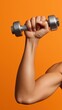 © OleksandrZastrozhnov - Close-up of female hand lifting dumbbell against vibrant orange background