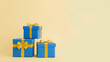 © Ася Андроник - A stack of three blue gift boxes with yellow ribbons against a soft yellow backdrop, perfect for celebrations.