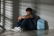 © New Africa - Teen problems. Upset teenage boy with backpack near light wall indoors