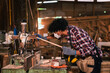 © DJ Creative Studio - Industrial Timber Factory Worker African American Man Using Tools in Sawmill with Focus, Skill, and Blue Collar Precision