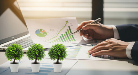 Poster - Businessperson reviewing financial charts and graphs, alongside potted plants, suggesting sustainable growth and eco-conscious business practices