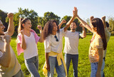 Happy diverse group of young people friends together in park, sunny outdoor, excited, celebrating achievement or victory gesture of triumph, success, unity, smiling joyful positive energy, high five
