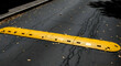 © DEVI - Bright Yellow Speed Bump On Cracked Asphalt Road In Autumn