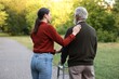 © New Africa - Caregiver supporting elderly man who using walking frame outdoors, back view
