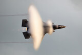 Modern fighter jet flying fast causing a vapor cone.