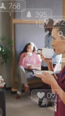 Poster - Animation of social media icons over two diverse women discussing while having coffee at office