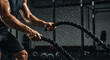 © Anna_Arts - An athlete intensely working out with battle ropes in a modern gym.