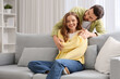 © Pixel-Shot - Apologizing young man hugging his wife on sofa at home