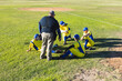 © Wavebreak Media - Coach and male teen baseball players gathering on sunlit infield diamond with gloves and helmets