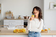 © Pixel-Shot - Young Asian woman drinking citrus infused water in kitchen