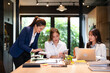 © Fahng - Confident youg businesswoman teaching interns or helping new employees in the organization, using laptop, sitting at desk in shared office, and colleagues working on online projects together.