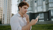 © Yuliia - Caucasian man using mobile phone smartphone social media chatting work online smiling communication internet app male guy student gadget networks business businessman walking street going city outdoor