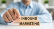 © Grafix71 - Person's hand placing wooden block with I N B O U N D M A R K E T I N G text on table business marketing