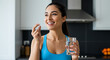 © Meiza - Woman taking pill with water in kitchen for health and wellness
