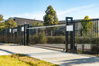 © Doublelee - Modern black steel security gate outside a contemporary public facility or school campus in Australia, featuring vertical bars, sliding mechanism, and mounted signage.