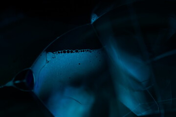 Fototapete - Blue liquid surfaceon black background, oil stains movement, bright chemistry, surreal background, arctic blue colour, water surface, ink and water